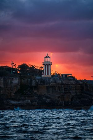 Hornby Lighthouse on the sandstone cliffs of South Head under a fiery sunset sky